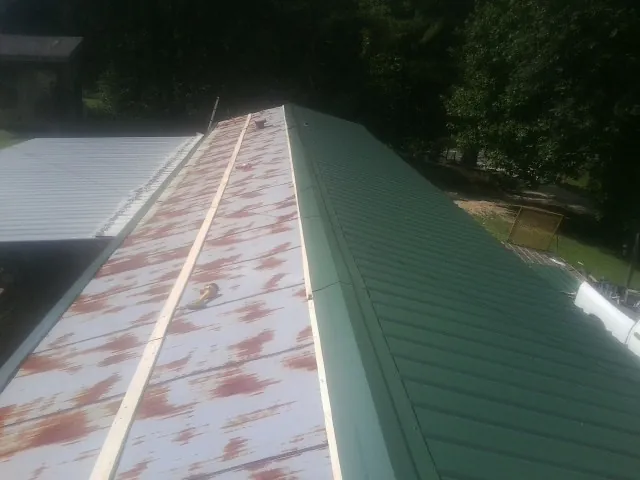 Old rusted panels beside newly installed green metal roofing — Wind Damage Roof Repair by Roofing Brothers in West Hyannisport