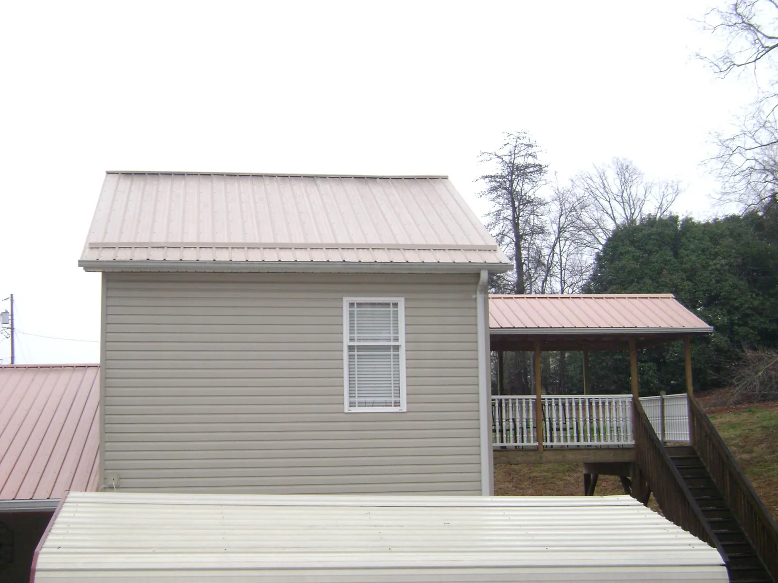 Tan metal roofs on a two story addition and attached porch, from a Roof Replacement job in West Hyannisport