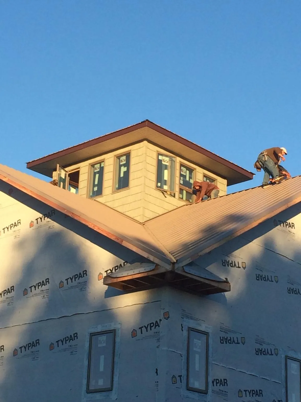 Roofers working around a rooftop cupola on a new metal roof at sunset — Roof Waterproofing in West Hyannisport by Roofing Brothers